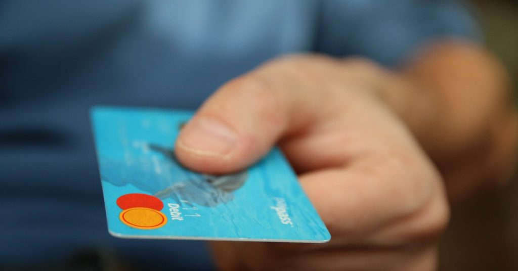 Man handing someone a debit card -Expanding Wallet