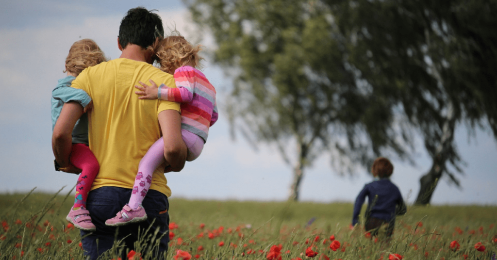 Man holding two kids and third kid running through flowers – Expanding Wallet